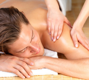 Happy handsome man getting a back massage by female hands. Enjoying a holiday at the beauty spa.